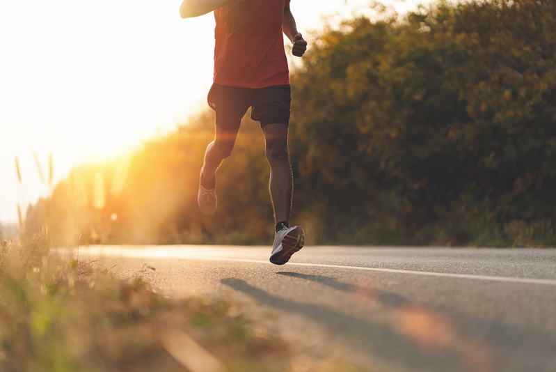 guy running at sunset on the side of a road