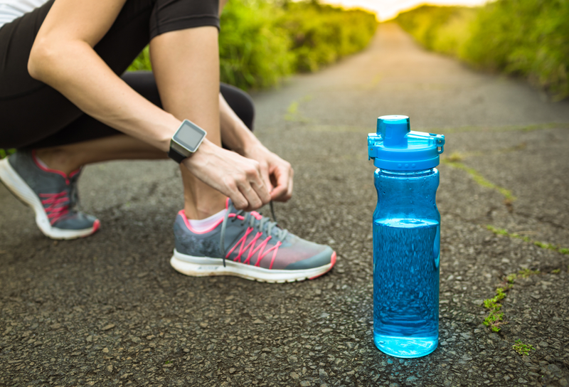 woman tying her shoe next to water bottle