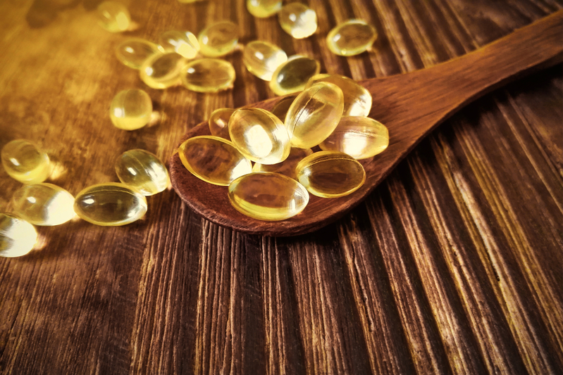 Vitamin D pills on a wooden spoon