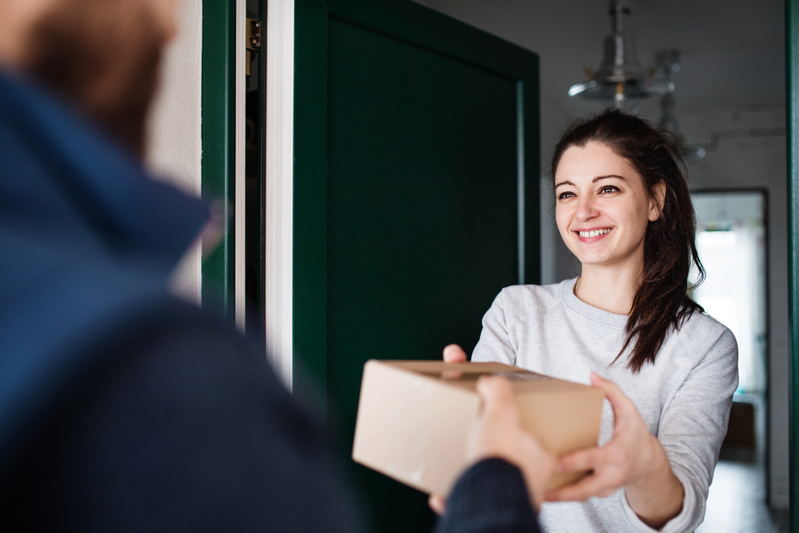 Man handing delivery to woman at door