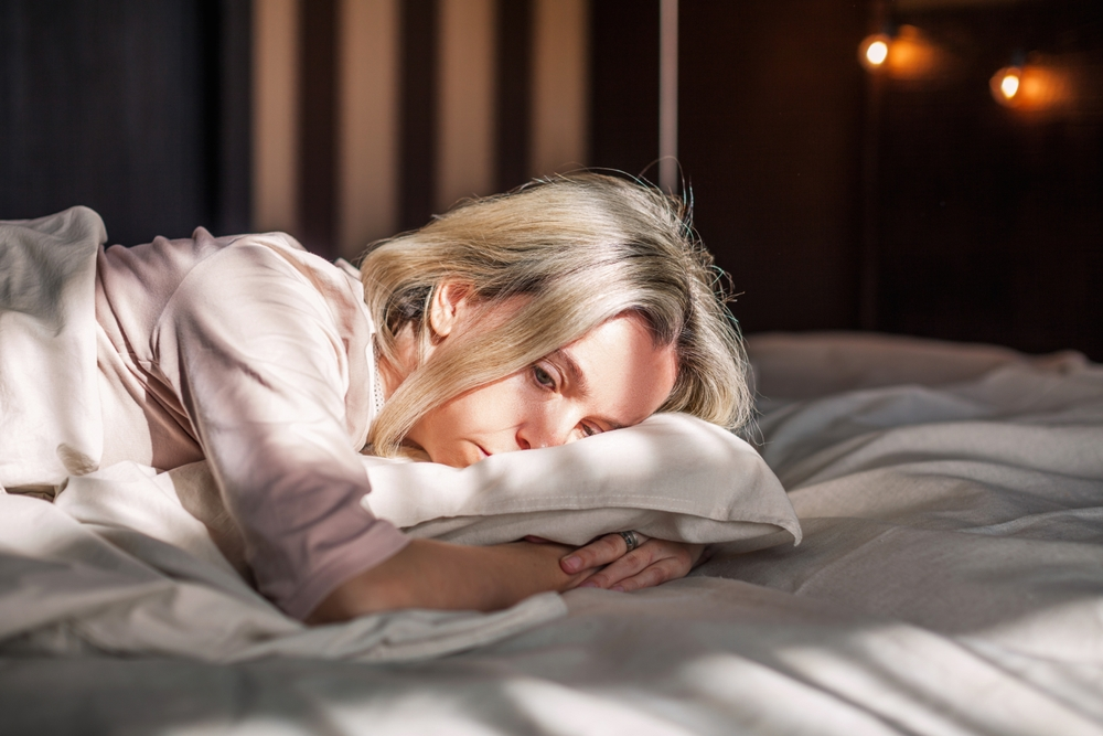 fatigued older woman laying on bed