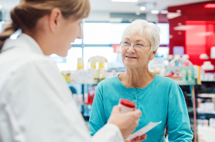 pharmacist handing prescription to woman