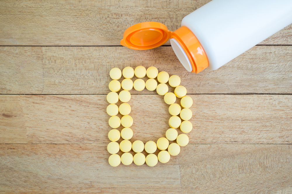 yellow pills arranged in the shape of a "D" on a wooden background