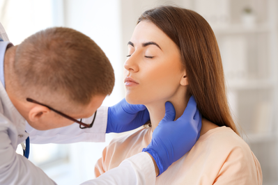 doctor checking woman's thyroid