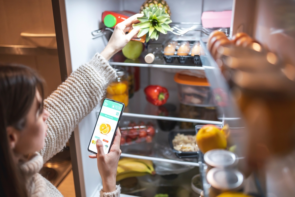 woman picking out food from fridge using diet app