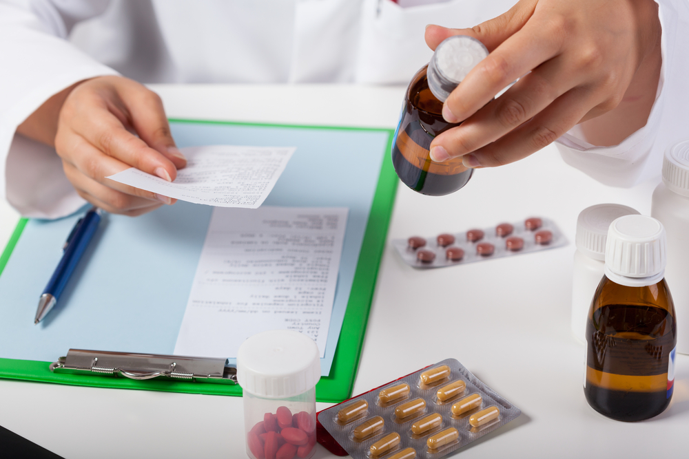 pharmacist checking medications against clipboard