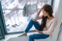 young woman with seasonal affective disorder staring out window