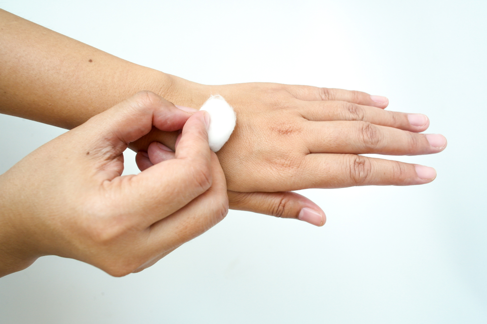 hand dabbing rubbing alcohol on wrist using cotton ball